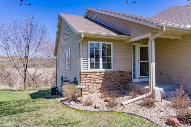 view of home's exterior featuring a yard, a shingled roof, and stone siding