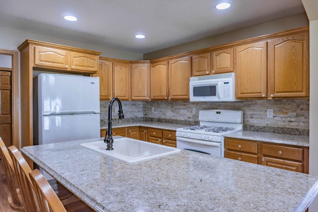 kitchen featuring white appliances, a breakfast bar, a sink, and light countertops