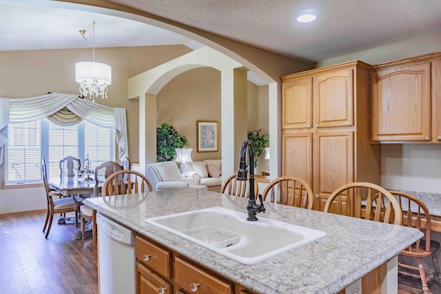 kitchen with white dishwasher, a sink, light countertops, arched walkways, and dark wood-style floors