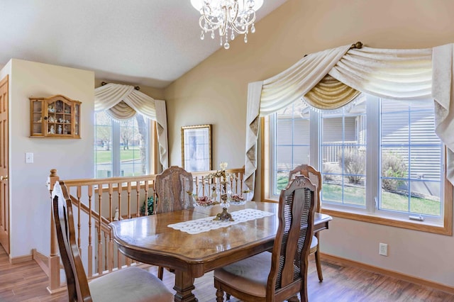 dining space with baseboards, vaulted ceiling, wood finished floors, and a notable chandelier
