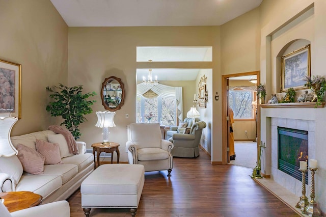 living area with plenty of natural light, a tile fireplace, wood finished floors, and a notable chandelier