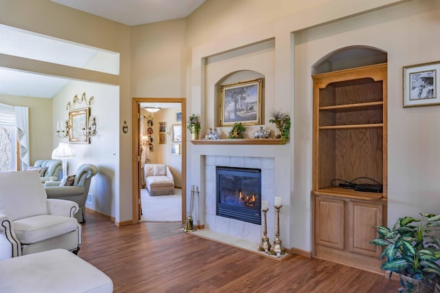 living room with baseboards, wood finished floors, and a tile fireplace