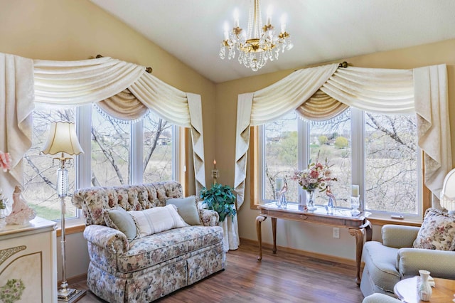 living area with baseboards, wood finished floors, a notable chandelier, and a wealth of natural light
