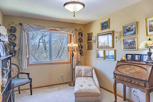 sitting room featuring carpet flooring, a textured ceiling, baseboards, and visible vents