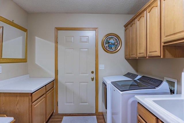 clothes washing area featuring cabinet space, a textured ceiling, dark wood finished floors, and washing machine and clothes dryer