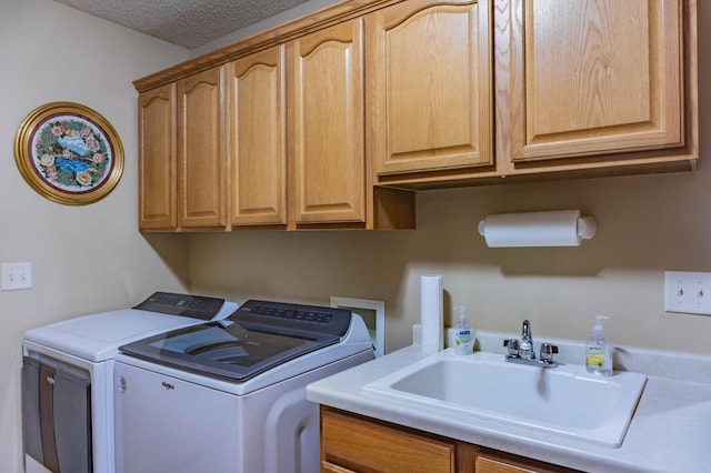 clothes washing area featuring a sink, a textured ceiling, cabinet space, and washer and dryer