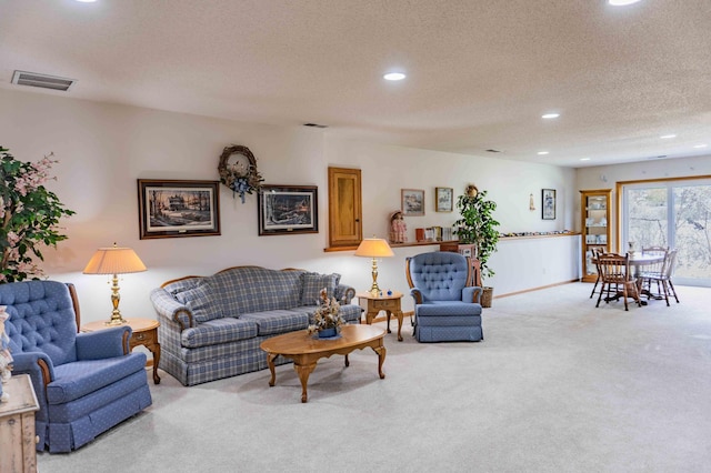 carpeted living room featuring recessed lighting, a textured ceiling, and visible vents