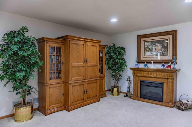living area featuring recessed lighting, baseboards, a glass covered fireplace, and light carpet