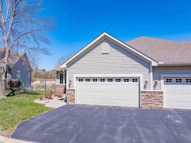 view of front of house with a front yard, aphalt driveway, and stone siding