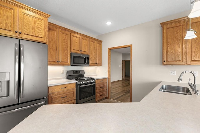 kitchen featuring a sink, light countertops, brown cabinetry, and stainless steel appliances