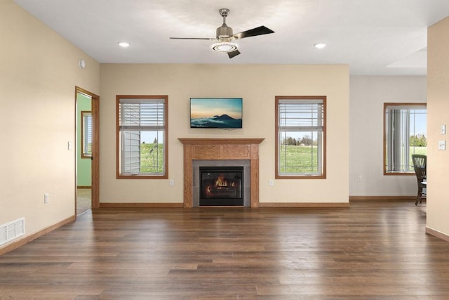 unfurnished living room with ceiling fan, a glass covered fireplace, baseboards, wood finished floors, and visible vents