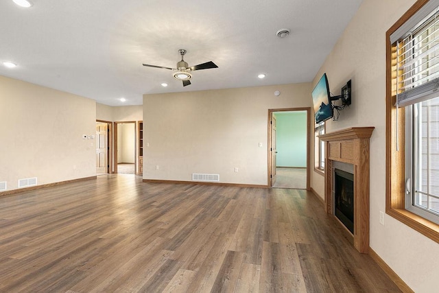 unfurnished living room with plenty of natural light, ceiling fan, wood finished floors, and visible vents