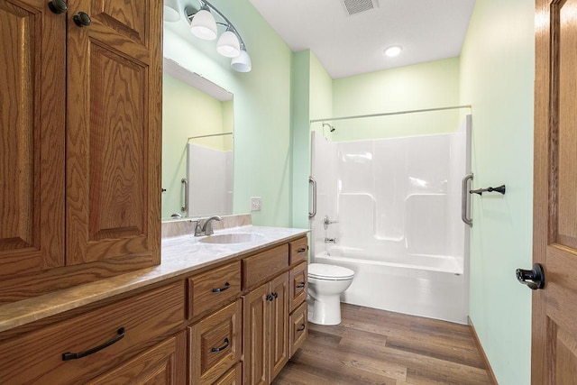 full bathroom with vanity, toilet, bathing tub / shower combination, wood finished floors, and visible vents