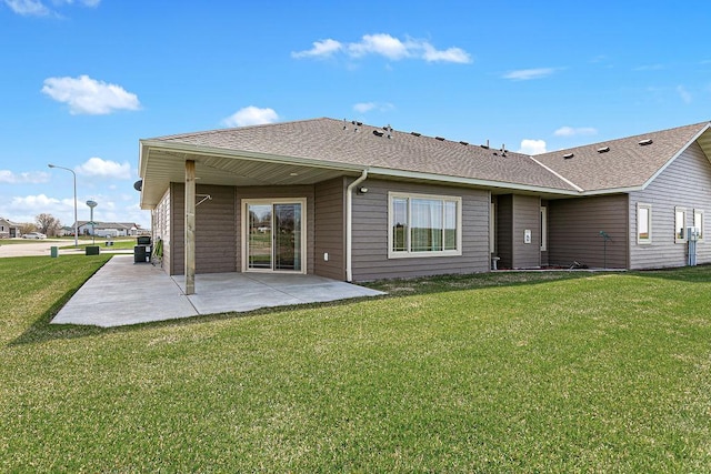 back of property featuring a lawn, a patio, and a shingled roof