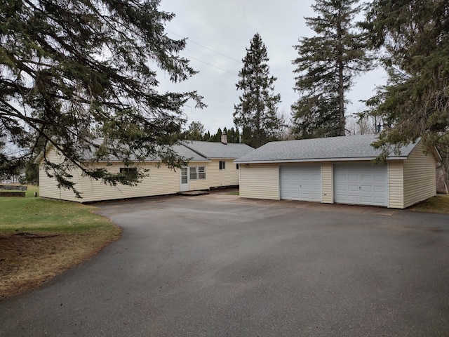 exterior space with a chimney, an outbuilding, and a garage