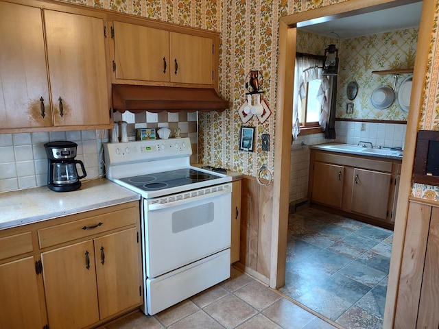 kitchen with a sink, custom exhaust hood, light countertops, wallpapered walls, and electric range