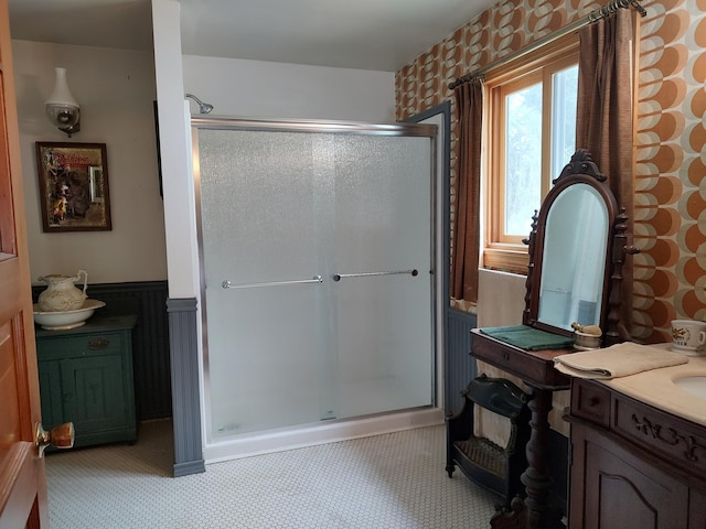bathroom with a stall shower, a wainscoted wall, and vanity