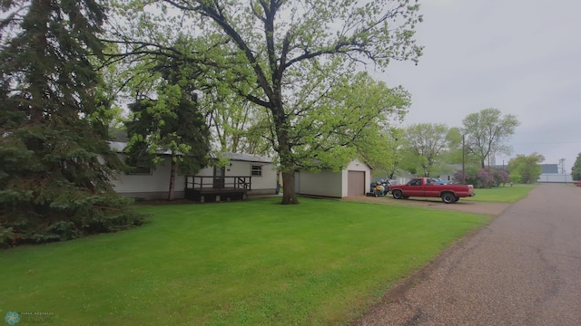 view of grassy yard with a detached garage and an outbuilding
