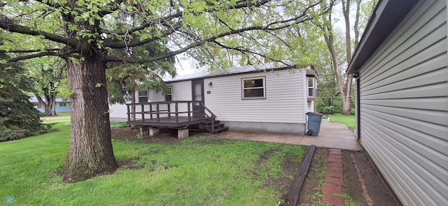 rear view of property with a yard, a wooden deck, and a patio