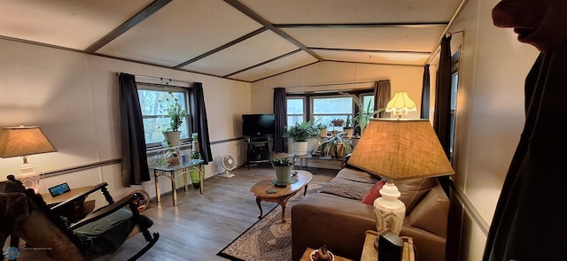 living area featuring vaulted ceiling, healthy amount of natural light, and wood finished floors