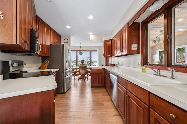 kitchen featuring a sink, recessed lighting, light wood finished floors, light countertops, and appliances with stainless steel finishes