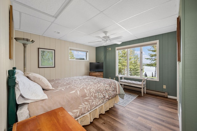 bedroom with a drop ceiling, ceiling fan, baseboards, and wood finished floors