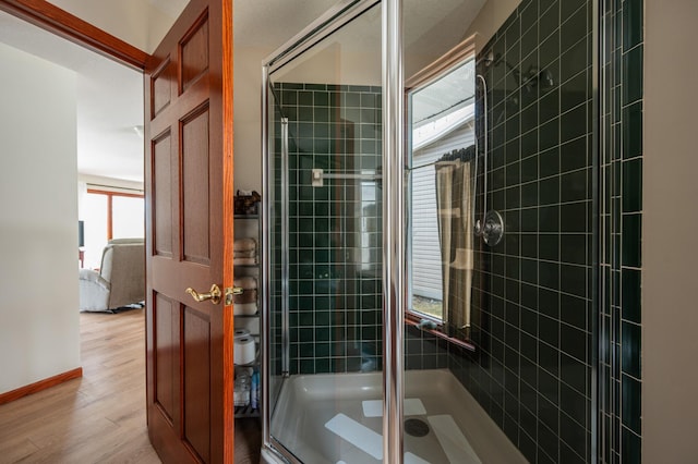 full bathroom featuring wood finished floors and a shower stall