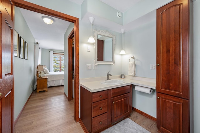 bathroom featuring baseboards, ensuite bath, vanity, and wood finished floors
