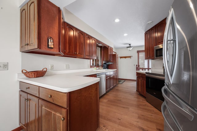 kitchen featuring a sink, appliances with stainless steel finishes, recessed lighting, light countertops, and light wood-style floors