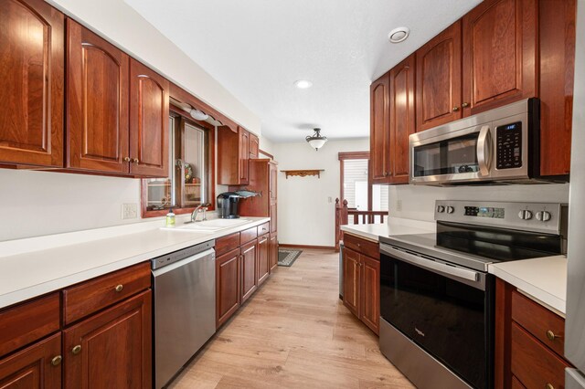 kitchen featuring recessed lighting, light wood finished floors, a sink, light countertops, and appliances with stainless steel finishes