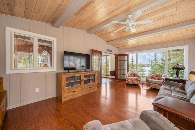 living area featuring a healthy amount of sunlight, vaulted ceiling with beams, and wood finished floors
