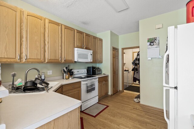 kitchen featuring white appliances, light wood-style floors, light countertops, a sink, and a textured ceiling