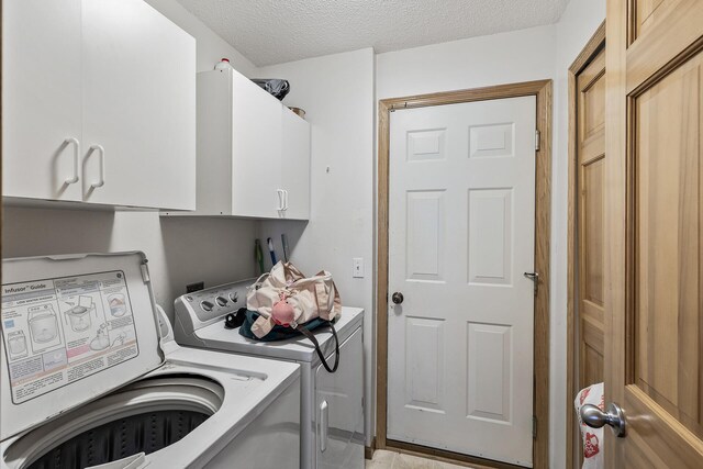 laundry room featuring washer and clothes dryer, cabinet space, and a textured ceiling