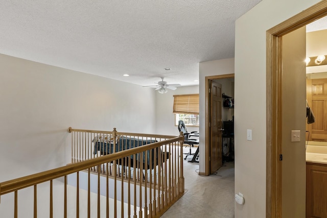 hallway with an upstairs landing, light colored carpet, a textured ceiling, and recessed lighting