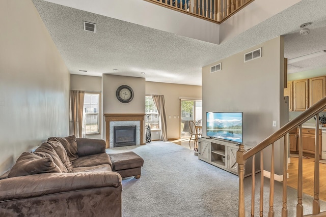 living room with a textured ceiling, a high end fireplace, light colored carpet, and stairs