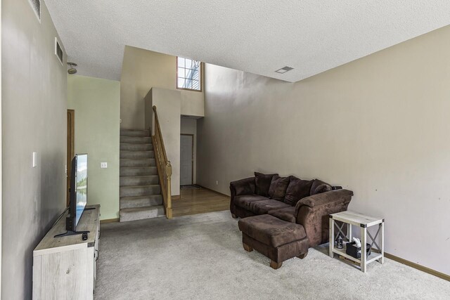 carpeted living room featuring stairway, a textured ceiling, and baseboards