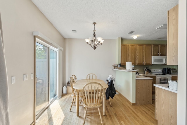 dining space with light wood-style floors, a chandelier, a textured ceiling, and baseboards