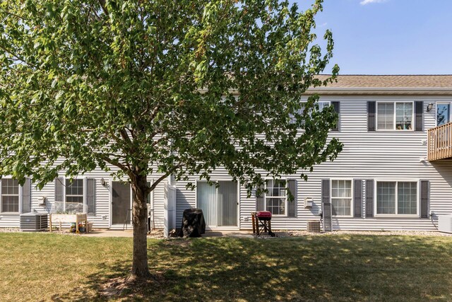 rear view of house featuring a lawn and cooling unit