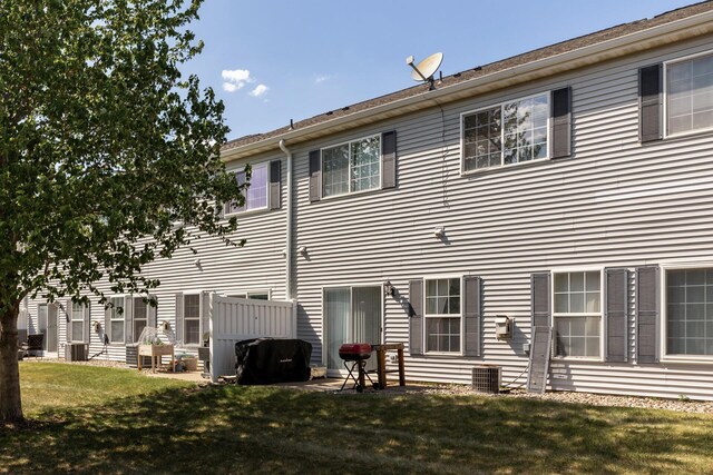 back of property with a yard and central AC