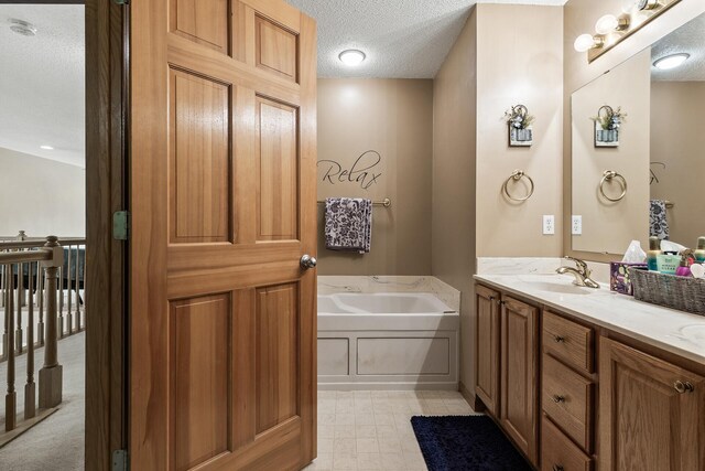 bathroom featuring a textured ceiling, a bath, and double vanity