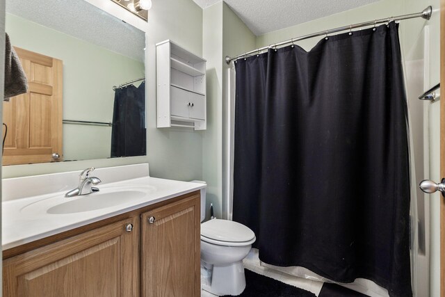 full bath with a textured ceiling, toilet, vanity, and a shower with curtain