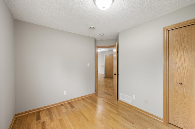 664 Highland Trl, Lino Lakes, MN 55014 - unfurnished bedroom with light wood-type flooring, a textured ceiling, and a closet