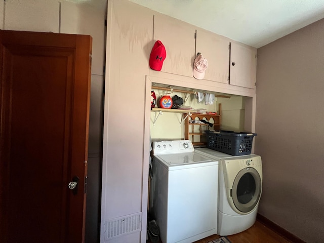 laundry room with wood finished floors, washing machine and clothes dryer, and cabinet space