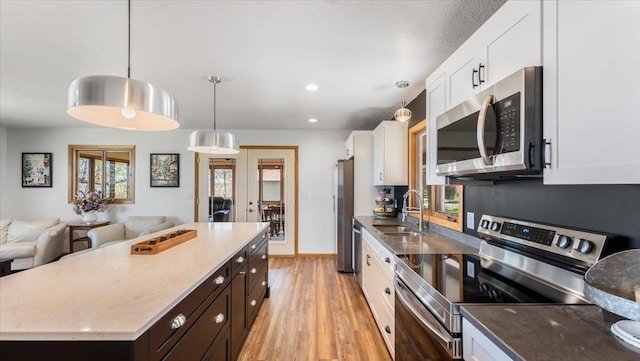7355 Little Mary Cir SW, Alexandria, MN 56308 - kitchen featuring appliances with stainless steel finishes, a sink, white cabinetry, open floor plan, and light wood-type flooring