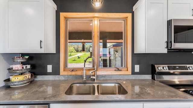7355 Little Mary Cir SW, Alexandria, MN 56308 - kitchen with appliances with stainless steel finishes, a sink, white cabinetry, and dark stone counters