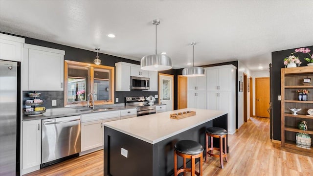 7355 Little Mary Cir SW, Alexandria, MN 56308 - kitchen featuring appliances with stainless steel finishes, a sink, a center island, a breakfast bar area, and light wood-style flooring