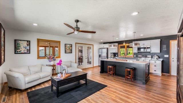 7355 Little Mary Cir SW, Alexandria, MN 56308 - living room with light wood-type flooring, a ceiling fan, recessed lighting, a textured ceiling, and baseboards