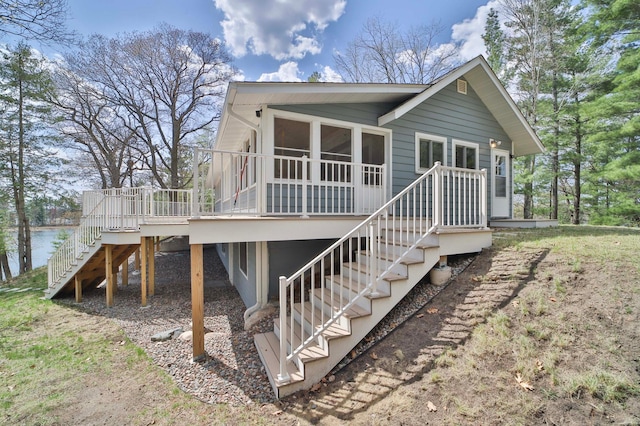 back of house featuring stairs, a sunroom, and a deck with water view