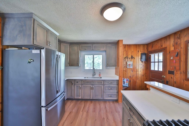 kitchen with freestanding refrigerator, a textured ceiling, light countertops, a sink, and light wood-style floors
