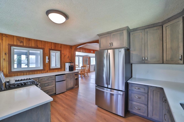 kitchen featuring freestanding refrigerator, fridge, gas stove, a textured ceiling, and arched walkways